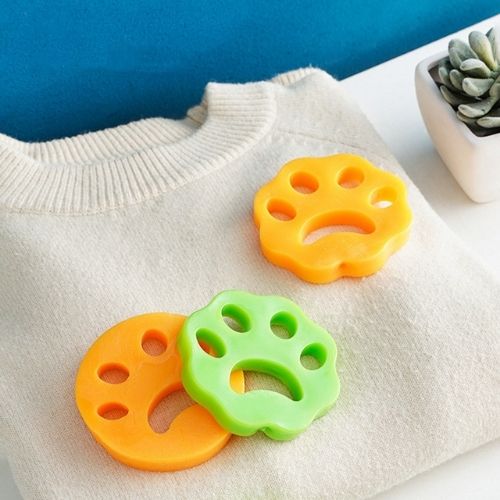 Pet Hair Remover set of three paw-shaped reusable hair catchers in orange and green, made of soft adhesive material.